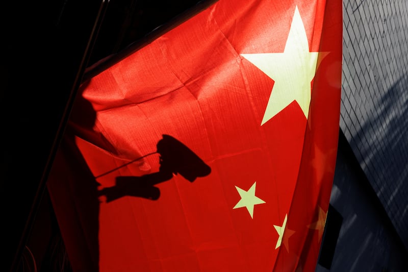 A surveillance camera is silhouetted behind a Chinese flag in Beijing, Nov. 3, 2022.